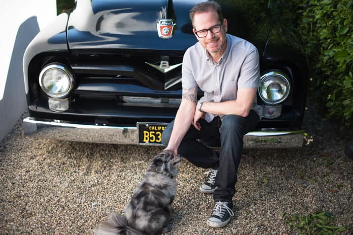 Dr. Sands kneeling with pet dog in front of his black Ford F100 Truck.